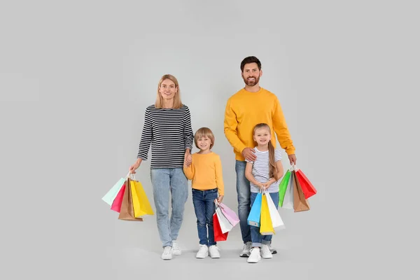 家庭购物 快乐的父母和孩子们 他们有许多色彩斑斓的书包 背景是浅灰色的 — 图库照片
