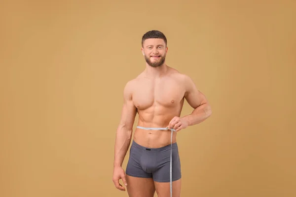 Atletische Man Meten Taille Met Tape Bruine Achtergrond Gewichtsverlies Concept — Stockfoto