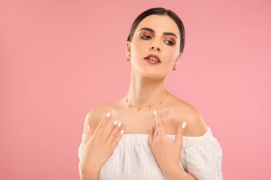 Pembe arka planda zarif mücevherleri olan güzel bir kadın.