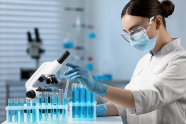 Bilim adamı laboratuardaki test tüpünden numune alıyor.