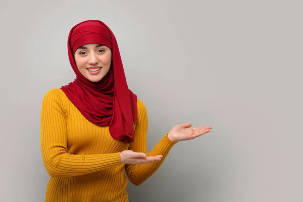 Muzułmanka Hidżabie Wskazująca Coś Jasnoszarym Tle Miejsce Tekst — Zdjęcie stockowe