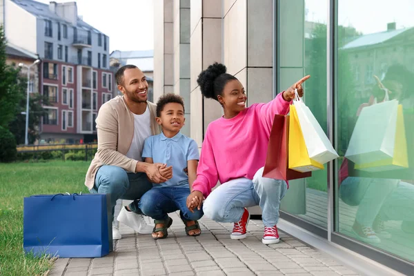 Aile alışverişi. Dışarıda alışveriş merkezinin yanında renkli çantaları olan mutlu bir aile ve oğul.