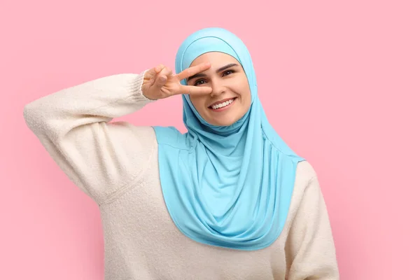 ヒジャーブのムスリム女性 ピンクの背景にVサインを表示 — ストック写真