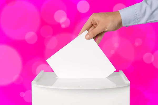 男人把他的选票放在粉红背景的投票箱里 — 图库照片
