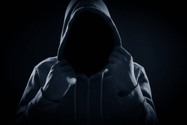 Anonymous man in hood on black background clipart