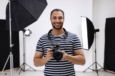 Modern fotoğraf stüdyosunda kamerası olan genç profesyonel fotoğrafçı.