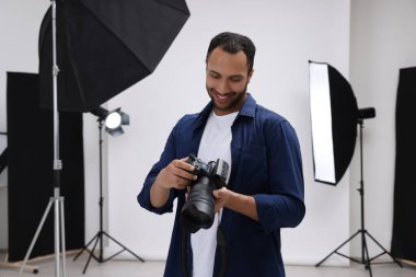 Modern fotoğraf stüdyosunda kamerası olan genç profesyonel fotoğrafçı.