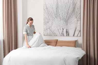 Genç hizmetçi otel odasında yatak yapma. Metin için yer