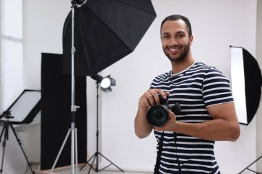Modern fotoğraf stüdyosunda kamerası olan genç profesyonel fotoğrafçı.