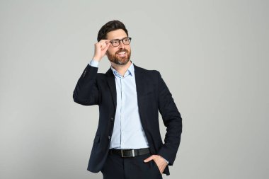 Gri arka planda takım elbiseli yakışıklı bir emlakçı.