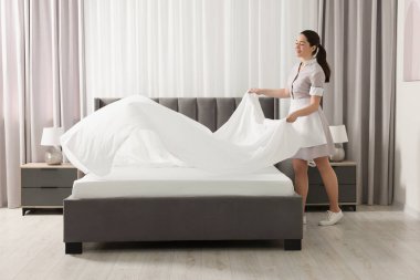 Genç hizmetçi otel odasında yatak yapma