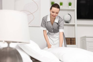 Genç hizmetçi otel odasında yatak yapma