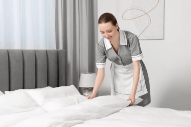 Genç hizmetçi otel odasında yatak yapma. Metin için yer