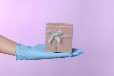 Doktor menekşe arkaplanda hediye kutusu tutuyor, yakın plan. Tıbbi hediye