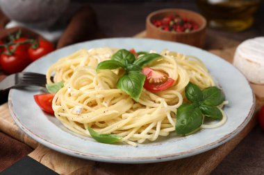Delicious pasta with brie cheese, tomatoes and basil leaves on table, closeup