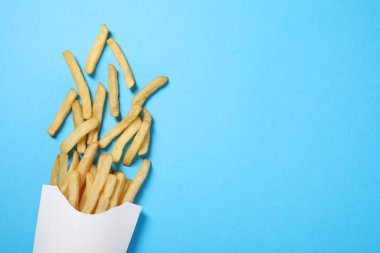 Açık mavi masada patates kızartmalı kağıt bardak, düz uzanmış. Metin için boşluk