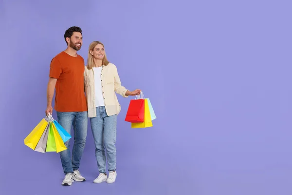 家庭购物 一对幸福的夫妇 有许多紫色背景的彩色包包 案文的篇幅 — 图库照片