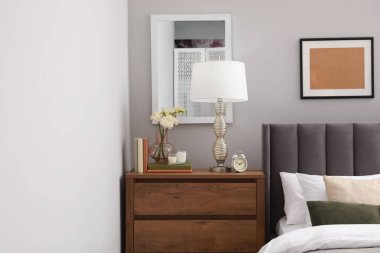 Yastıkları, lambası ve odasındaki ahşap çekmecelerde farklı dekorları olan rahat bir yatak. Şık iç mekan