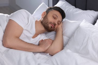 Evdeki yumuşak yatakta uyuyan yakışıklı adam.
