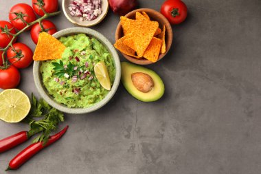 Bir kase lezzetli guacamole, cips ve malzemeler gri masada, düz konumda. Metin için boşluk