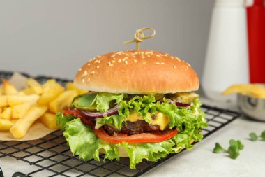 Biftek köfteli lezzetli burger ve beyaz masada marul, yakın plan.