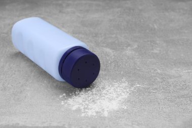 Gri masa üzerinde şişe ve dağınık bebek pudrası, metin için boşluk