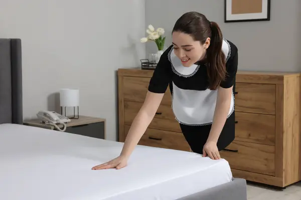 stock image Young chambermaid making bed in hotel room