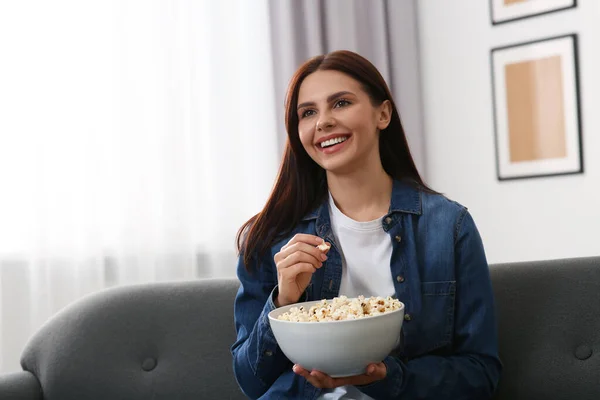 快乐的女人带着一碗爆米花在家里看电视 — 图库照片