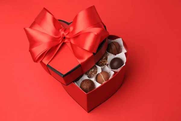 红桌上有好吃的巧克力糖果的心形盒子 — 图库照片