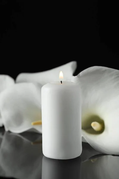 白いキャンドルと白いキャラリーの花を暗闇の中で黒いミラーの表面に燃やし テキストのためのスペースで閉じます 葬儀シンボル — ストック写真