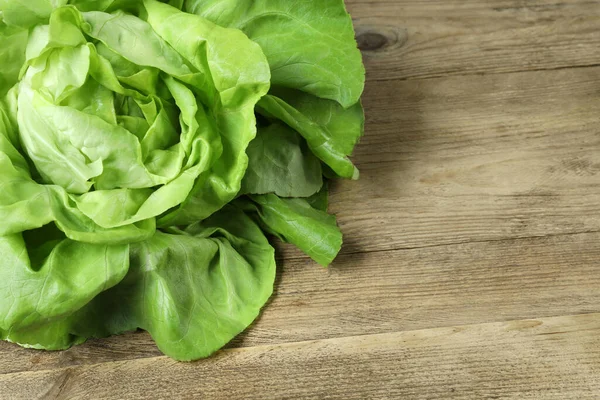 Fresh green butter lettuce on wooden table, space for text