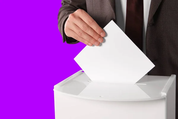 彼の投票をバイオレットの背景に投票ボックスに置いた男 クローズアップ — ストック写真