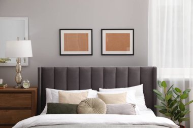 Yastıkları, lambası ve odasındaki ahşap çekmecelerde farklı dekorları olan rahat bir yatak. Şık iç mekan