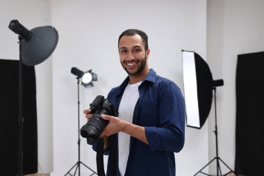 Modern fotoğraf stüdyosunda kamerası olan genç profesyonel fotoğrafçı.