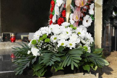 Mezarlıktaki granit mezar taşında çiçek çelengi