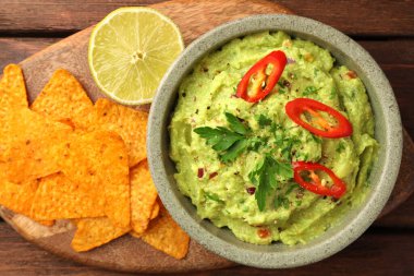 Bir kase lezzetli guacamole, limon ve cips, ahşap masa, üst manzara