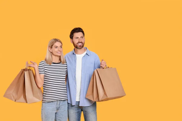 Aile Alışverişi Turuncu Arka Planda Kağıt Torbaları Olan Mutlu Bir — Stok fotoğraf