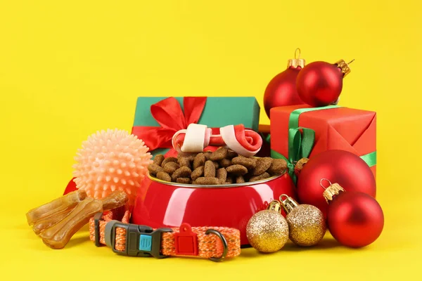 Different pet goods with Christmas gifts on yellow background. Shop assortment