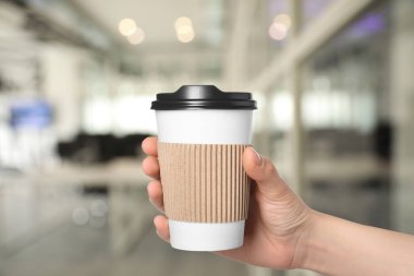 Paket kahve. Arka planda kağıt bardak sıcak içecek tutan kadın, yakın plan.