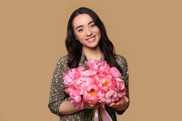 ライトブラウンの背景にピンクのコニーの花束を持つ美しい若い女性 — ストック写真