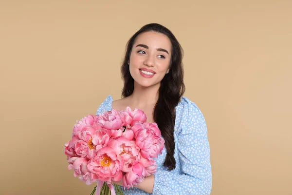 ベージュの背景にピンクのコニーの花束を持つ美しい若い女性 — ストック写真
