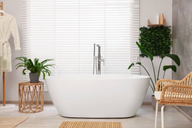 Banyoda yeşil yapay bitkiler ve beyaz küvet