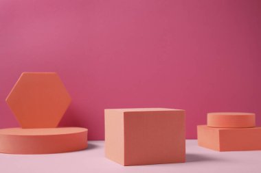 Birçok turuncu geometrik figür pembe arka plana karşı, metin için boşluk. Ürün için stil sunumu