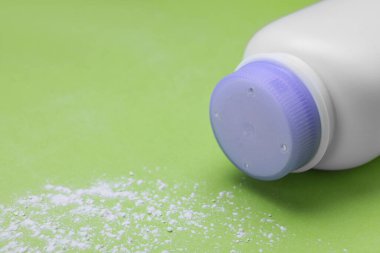 Açık yeşil arka planda şişe ve toz alma tozu, metin için alan. Bebek kozmetik ürünü