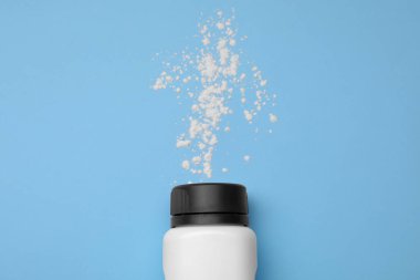 Açık mavi arka planda şişe ve toz alma tozu, üst manzara. Bebek kozmetik ürünü