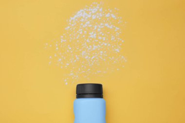 Sarı arka planda şişe ve toz alma tozu, üst manzara. Bebek kozmetik ürünü