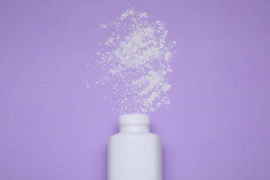 Mor arka planda şişe ve toz alma tozu, üst manzara. Bebek kozmetik ürünü