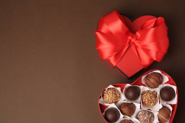 Kahverengi arka planda lezzetli çikolata şekerleri olan kalp şeklinde bir kutu. Metin için boşluk