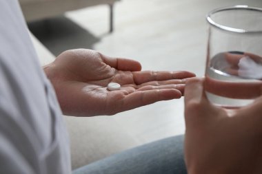 Bulanık arka planda bir bardak su ve hap olan adam, yakın plan.