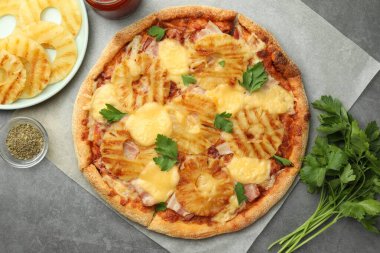 Lezzetli ananaslı pizza ve gri masadaki malzemeler.